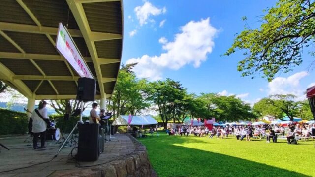 音楽クリエイター日景健貴が小坂中央公園のステージでライブをしている写真