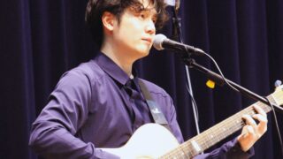 日景健貴がライブでギター弾き語りをしている写真
