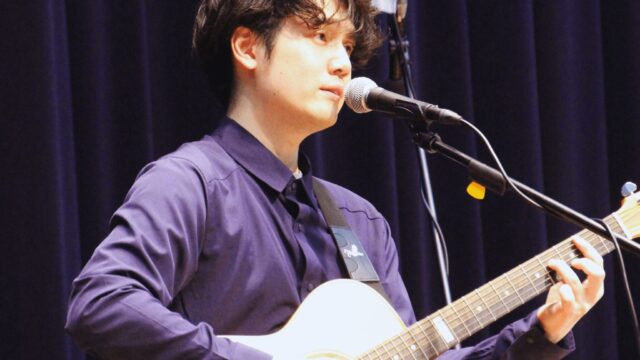 日景健貴がライブでギター弾き語りをしている写真
