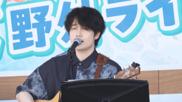 トラックの上でギターを弾き語りしている音楽クリエイター日景健貴の写真