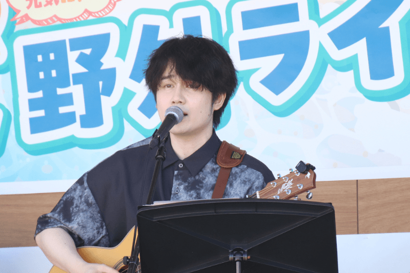 トラックの上でギターを弾き語りしている音楽クリエイター日景健貴の写真